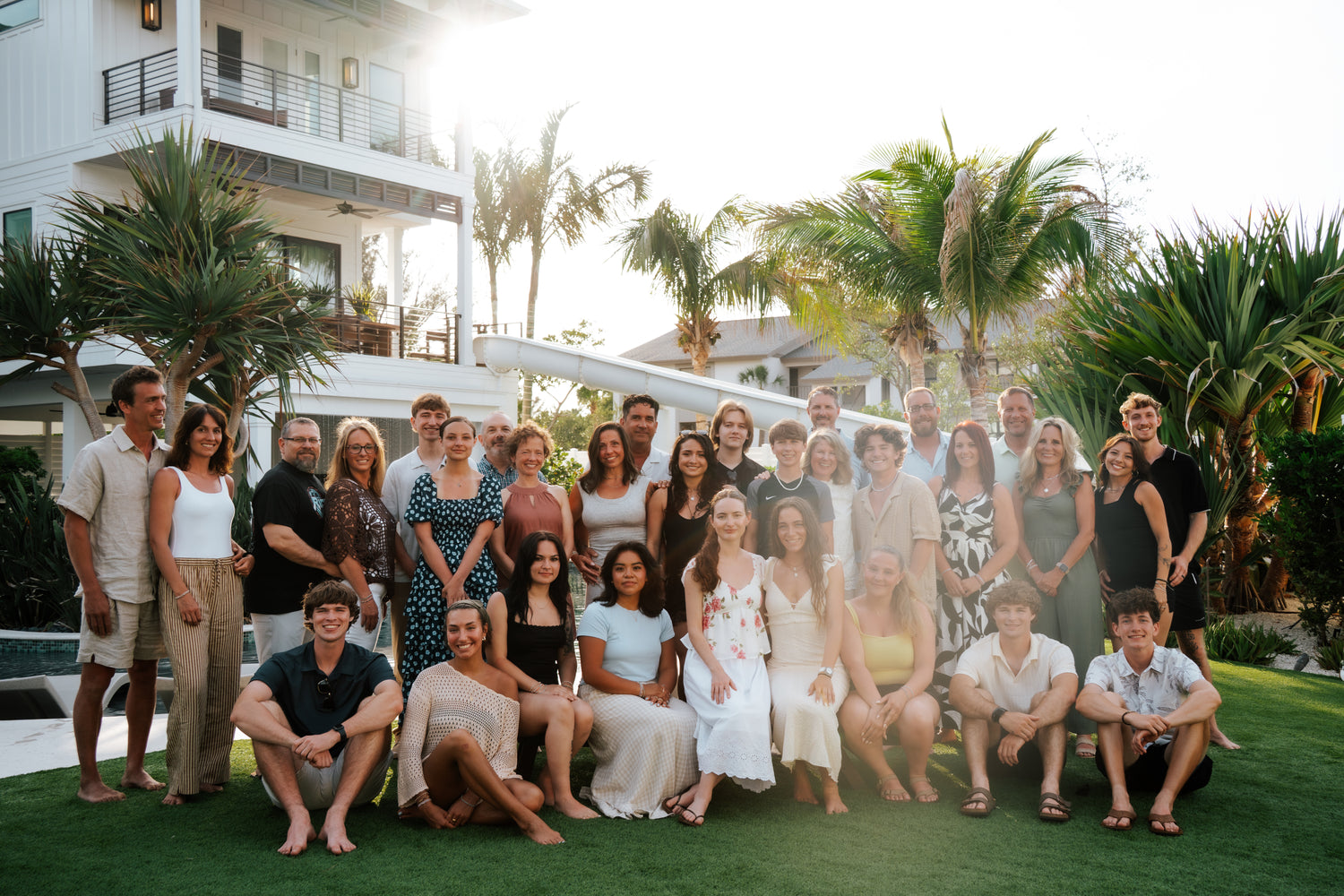Group of people posing for a photo in front of a house with palm trees.