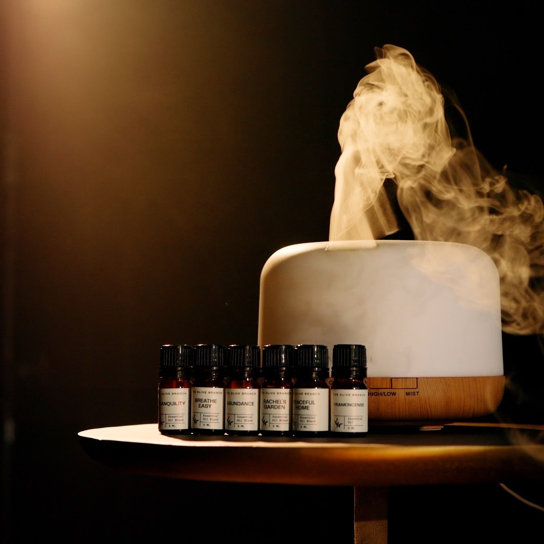 Aromatherapy diffuser with steam and essential oil bottles on a dark background