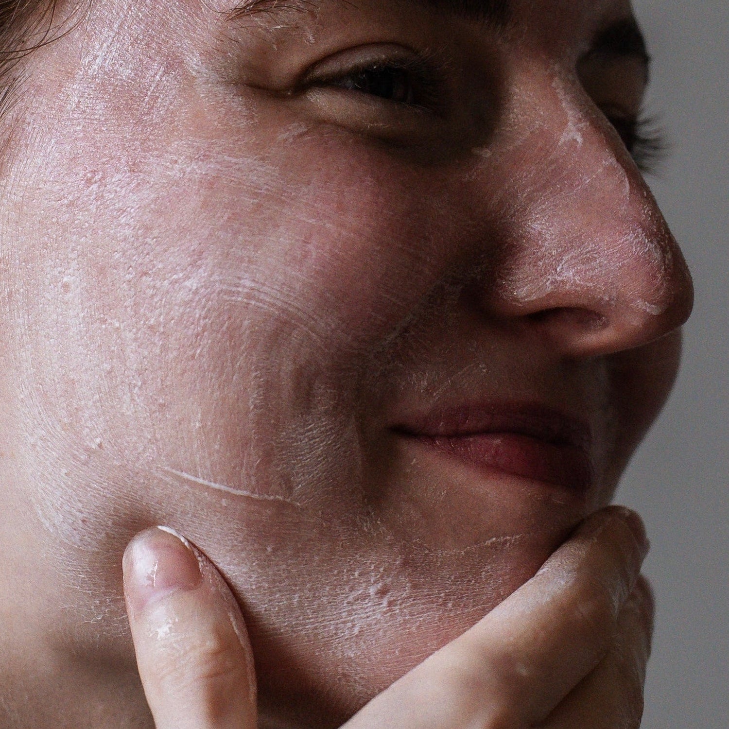 Woman washing face in a neutral indoor setting