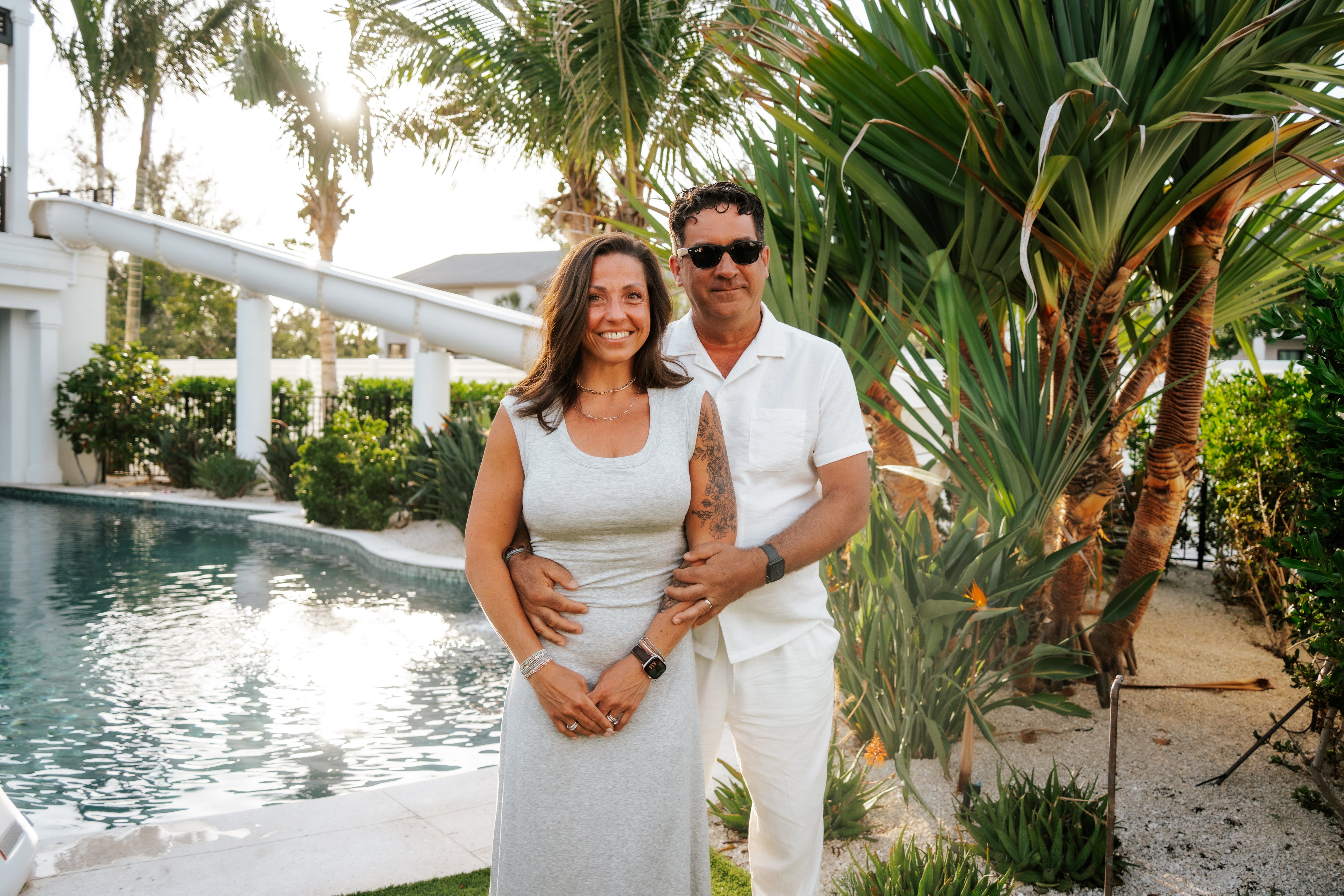 Couple standing by a pool with palm trees in the background