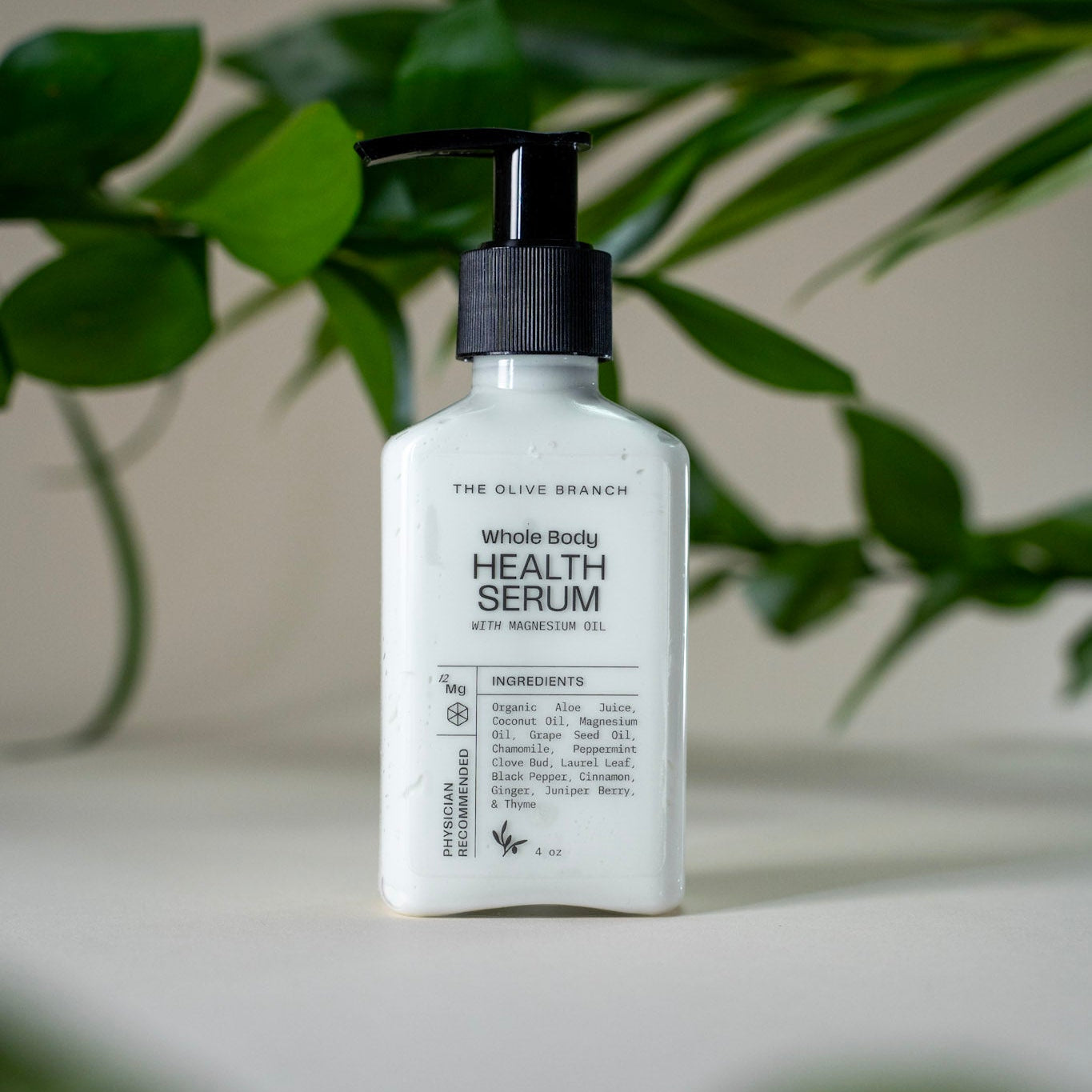 Whole Boddy Health Serum bottle with pump on a light surface with green leaves in the background