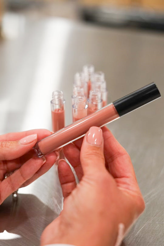 Person holding organic tinted lip balm in hands with eight organic tinted lip balms in the background.