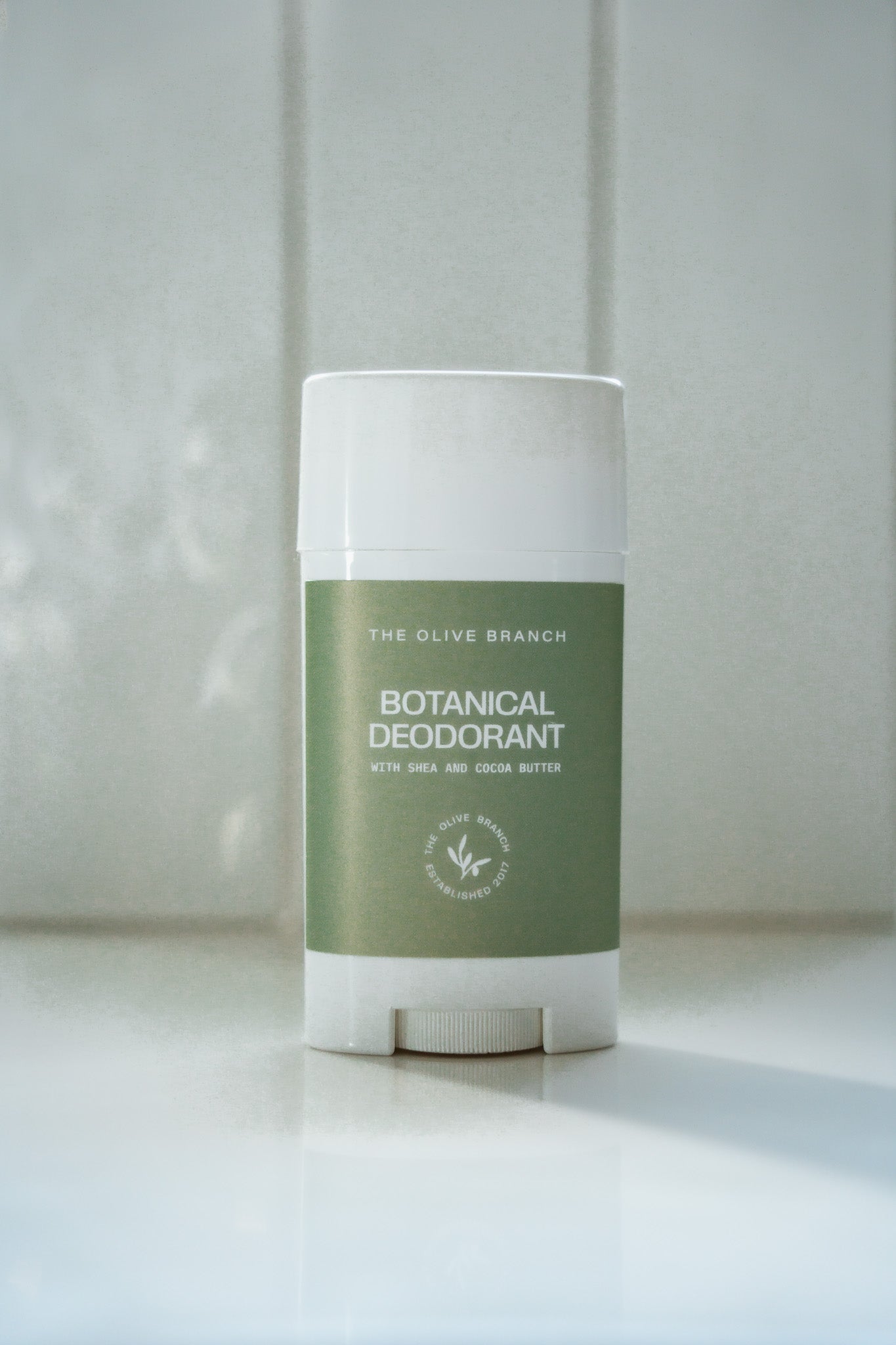 Botanical deodorant stick with green label on a white surface