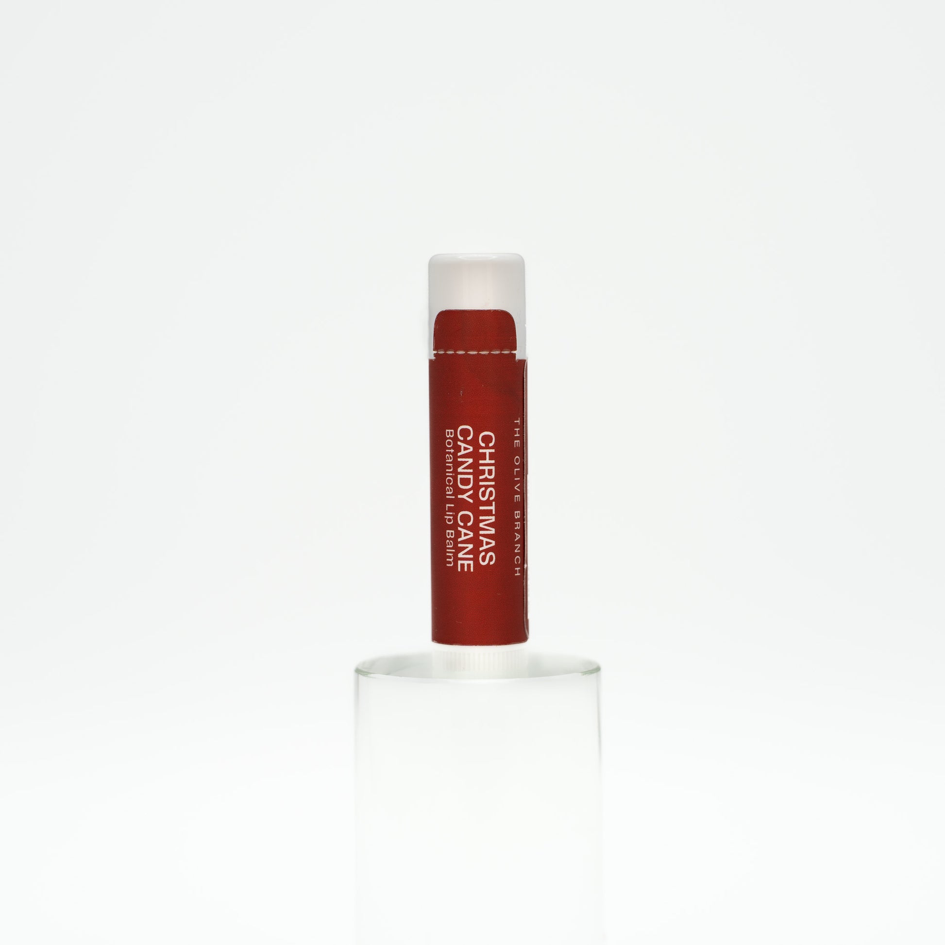 Lip balm with red stick and white cap on a white background