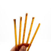 Hand holding five raw honey sticks against a white background