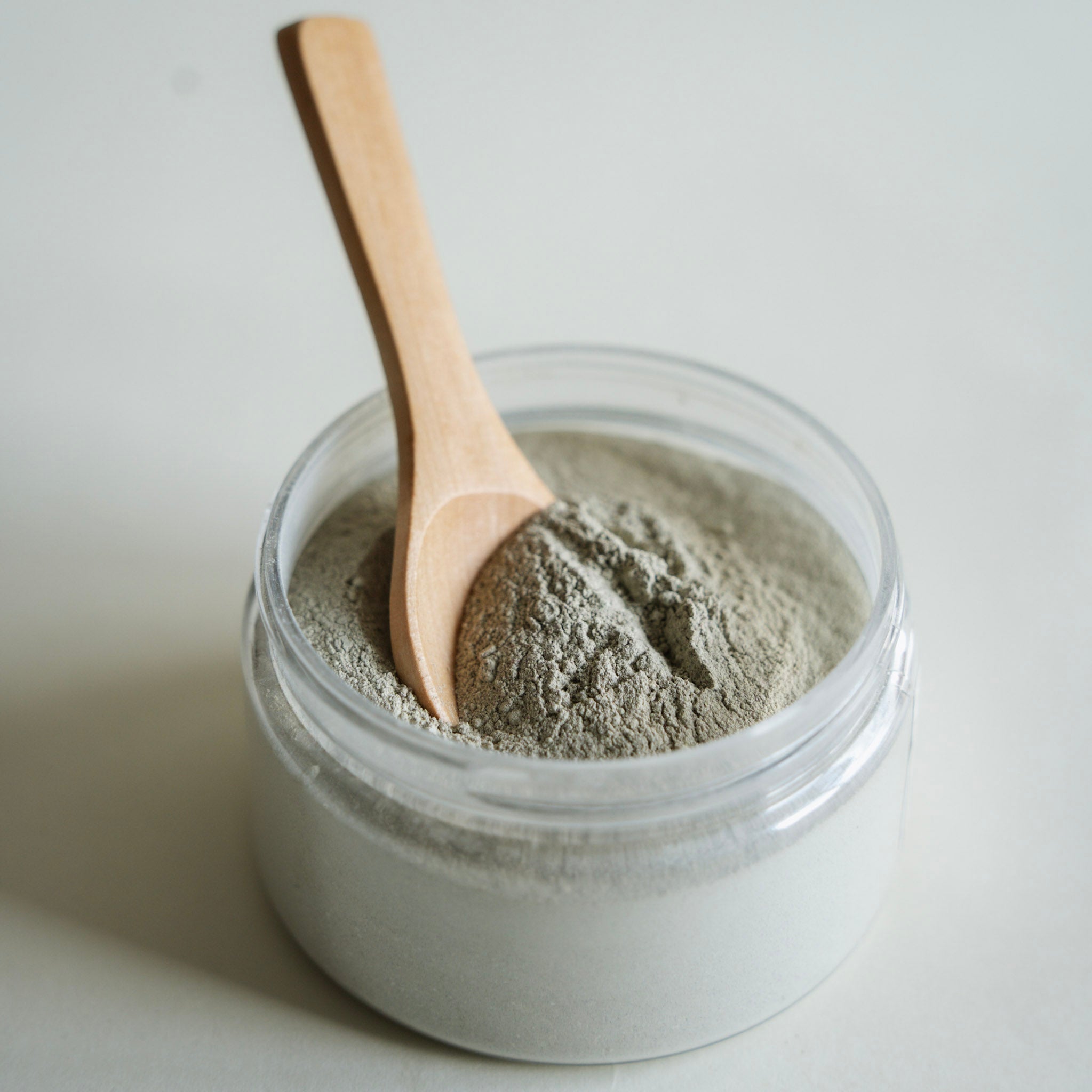 Jar of a facial mask with a wooden spoon on a light background