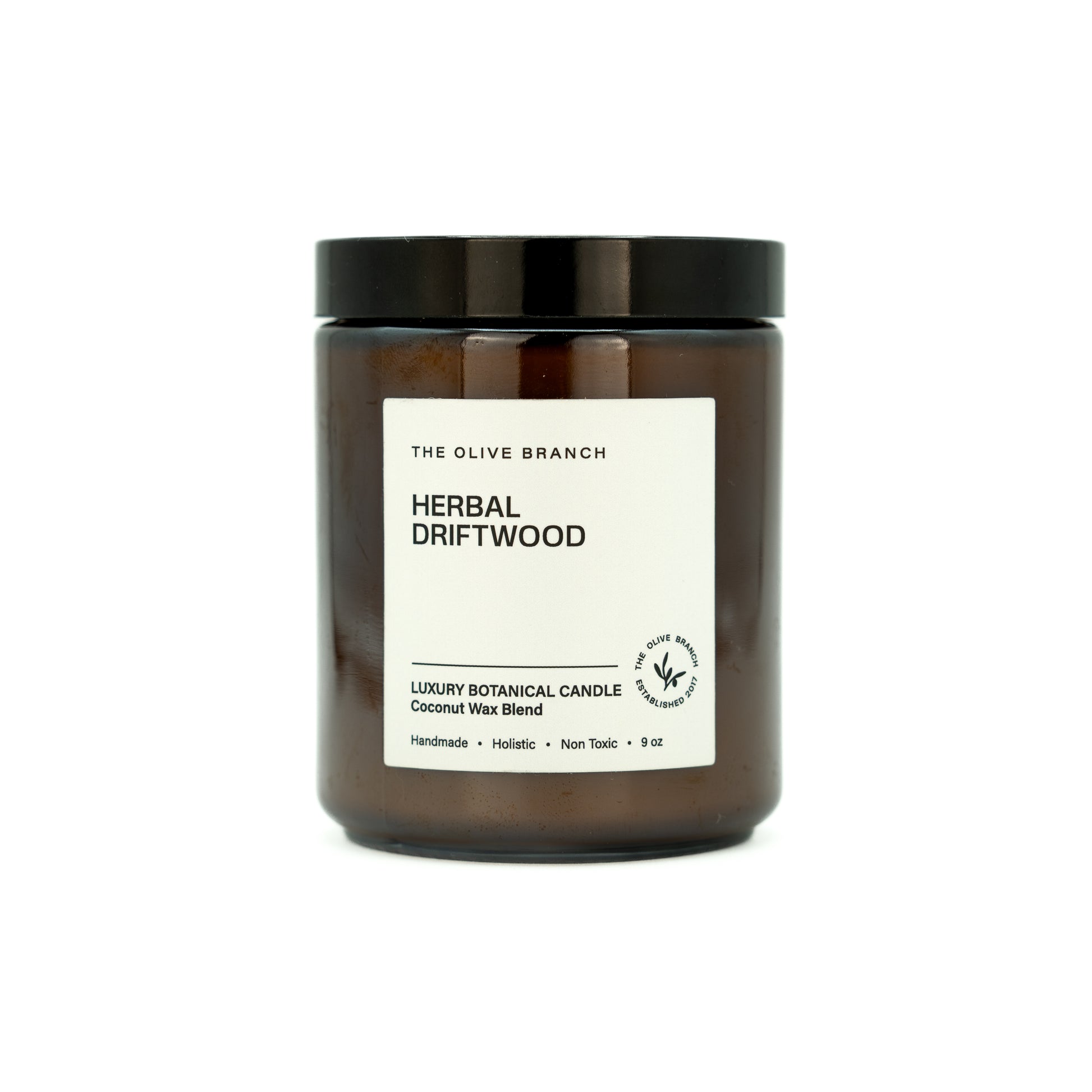 Candle jar labeled 'Herbal Driftwood' by 'The Olive Branch' on a white background