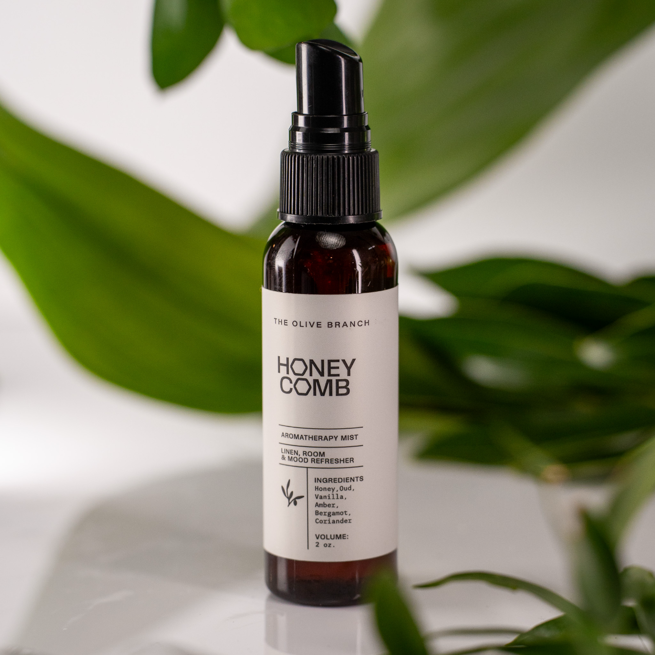 Honey Comb aromatherapy mist bottle with a white label against a green leafy background
