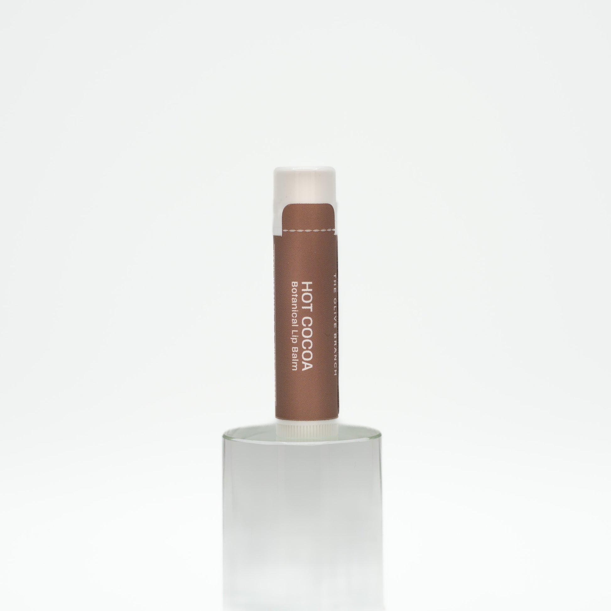 Hot Cocoa lip balm in a white container on a light beige background