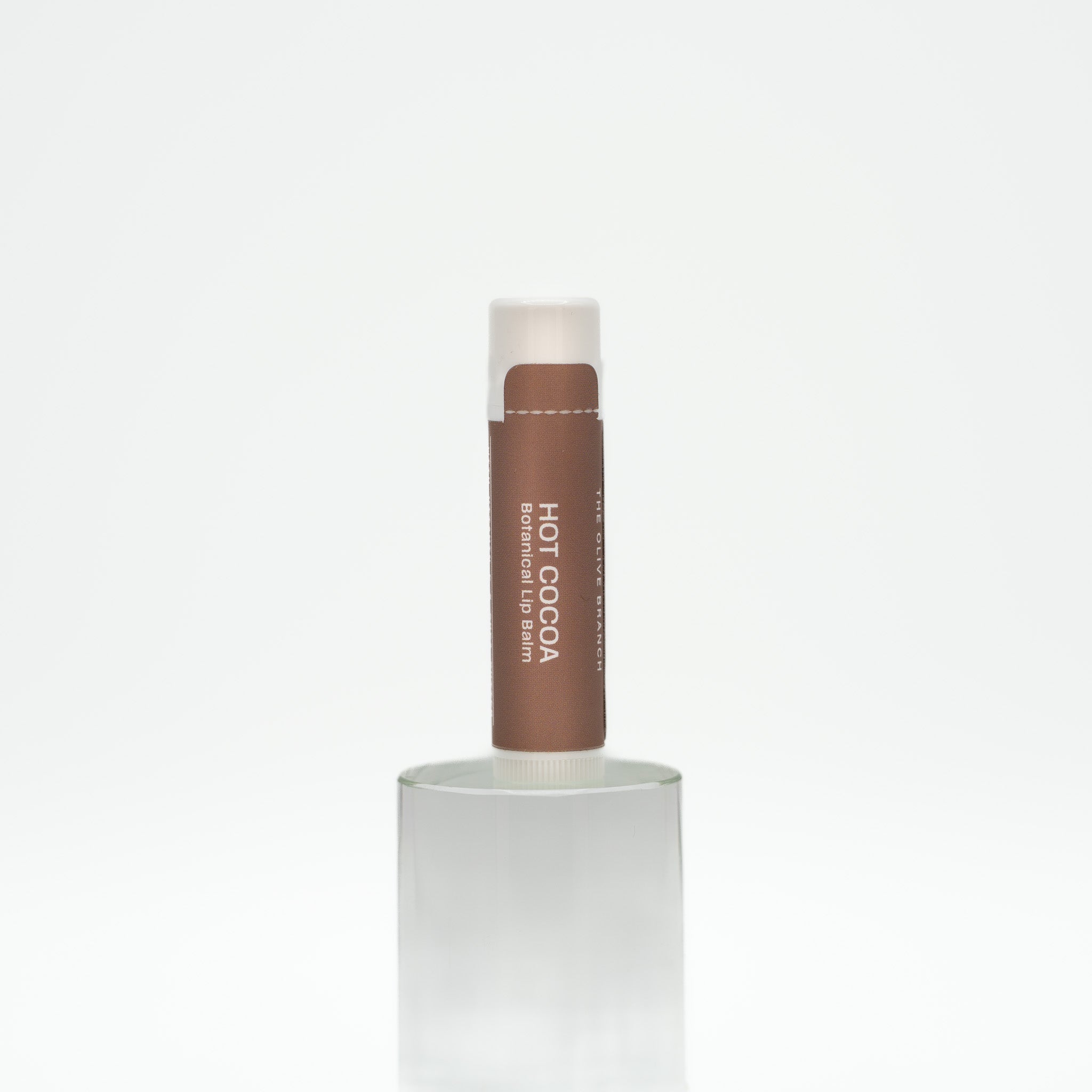 Hot Cocoa lip balm in a white container on a light beige background