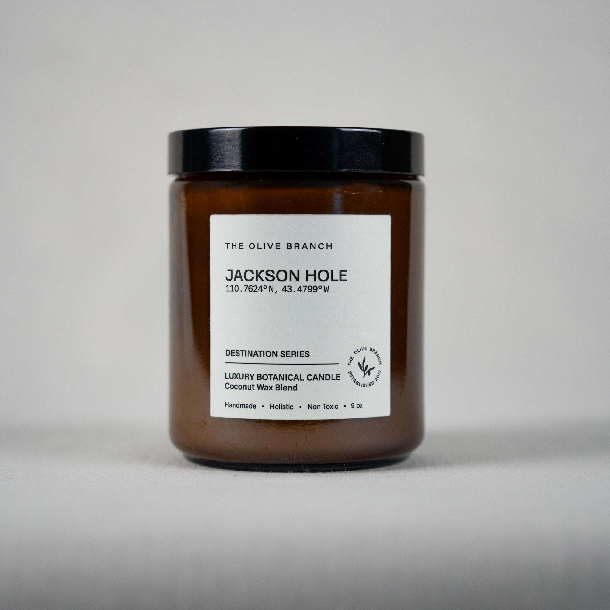 Candle jar with a label 'Jackson hole' on a gray background