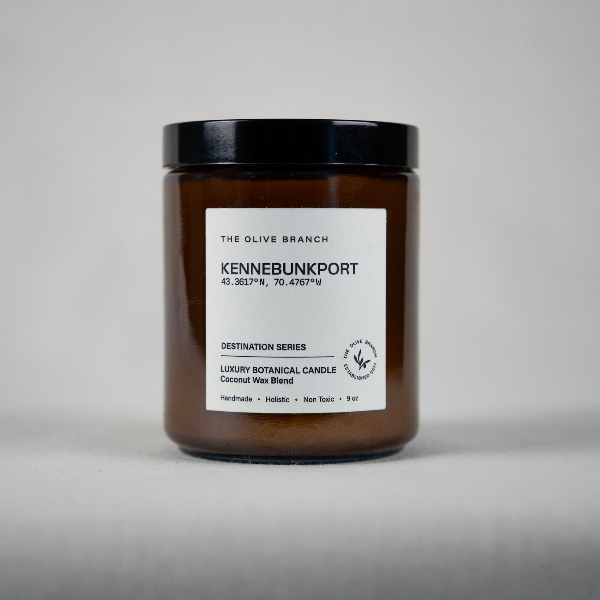 Brown candle jar 'Kennebunkport' with black lid and white label on a gray background