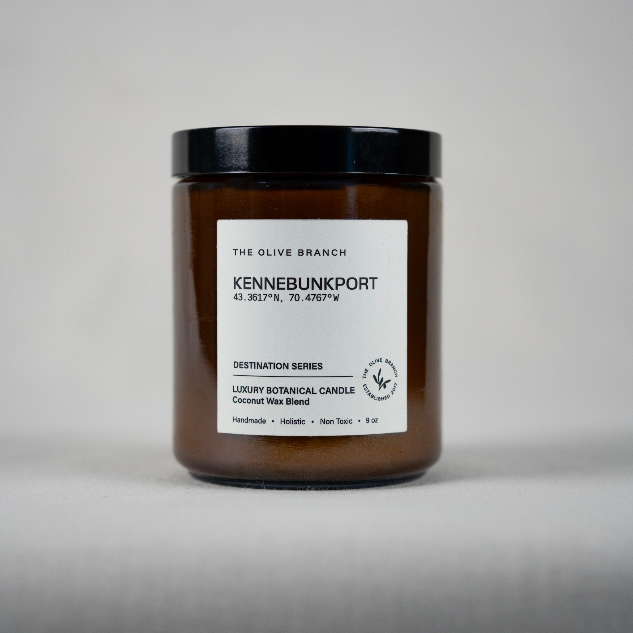 Brown candle jar 'Kennebunkport' with black lid and white label on a gray background