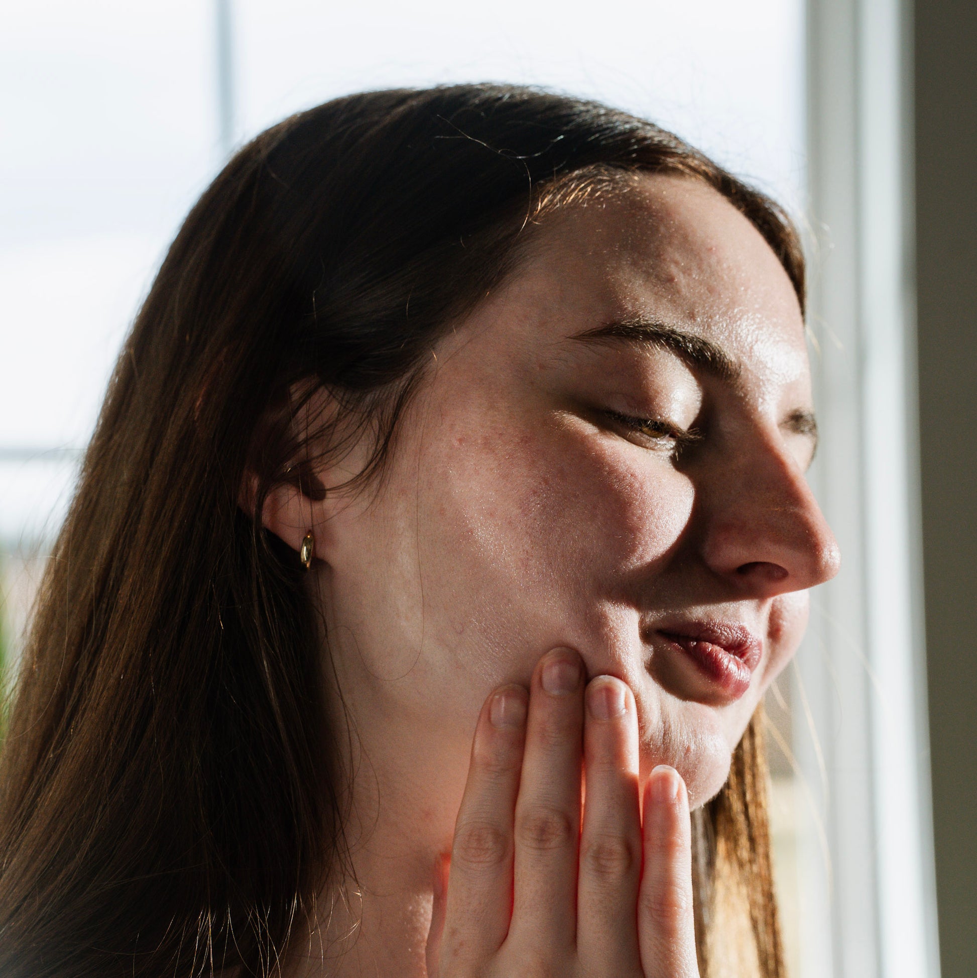 Woman applying optimal healing facial and body oil on her skin.