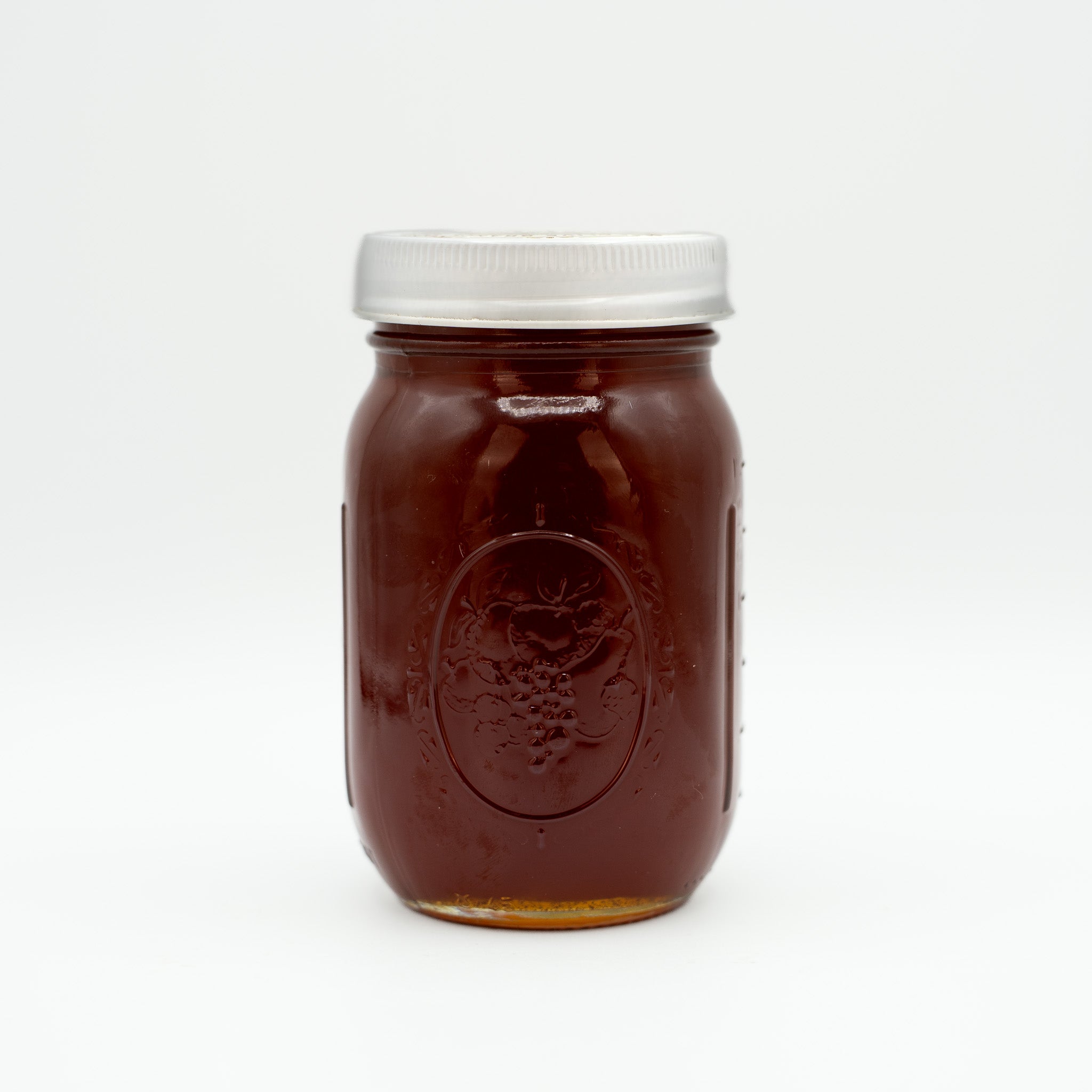 Jar of local honey with a silver lid on a white background