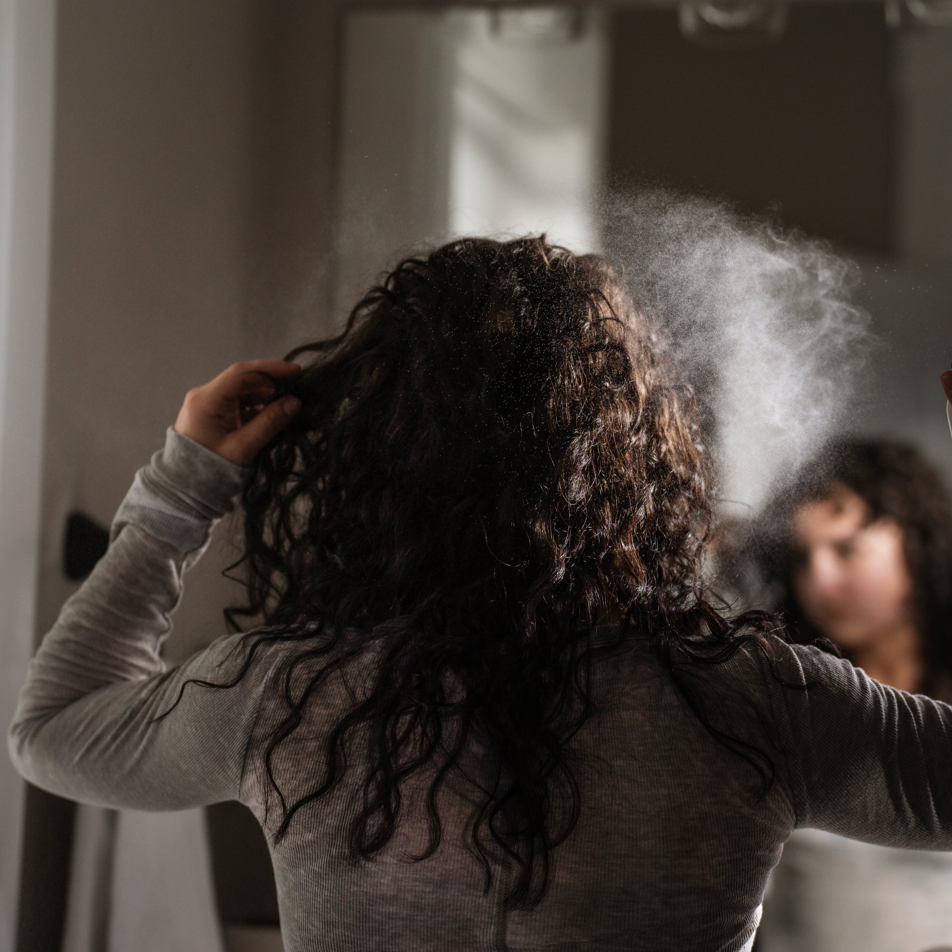 Person with curly hair using the Rose Water mist.