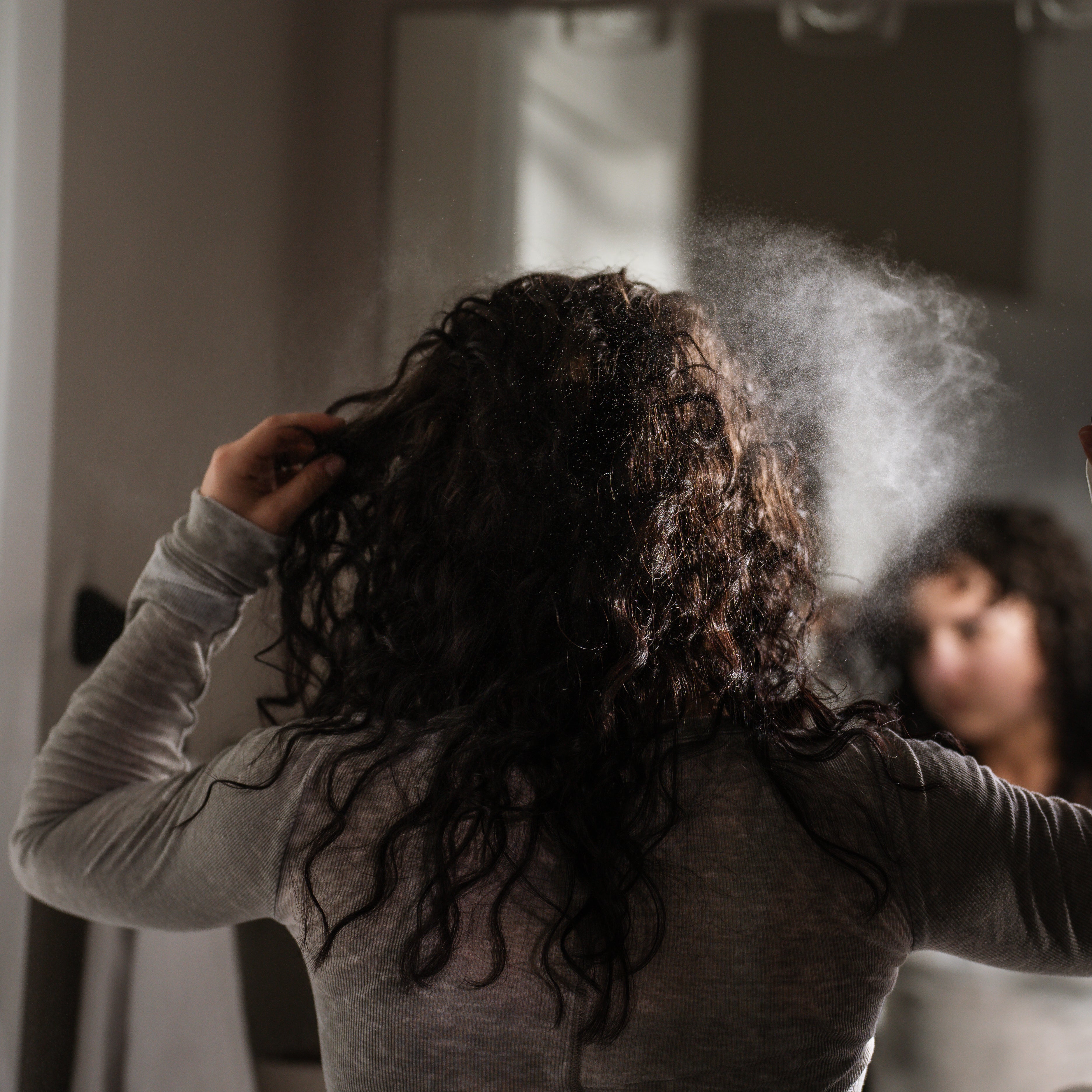 Person with curly hair using the Rose Water mist.