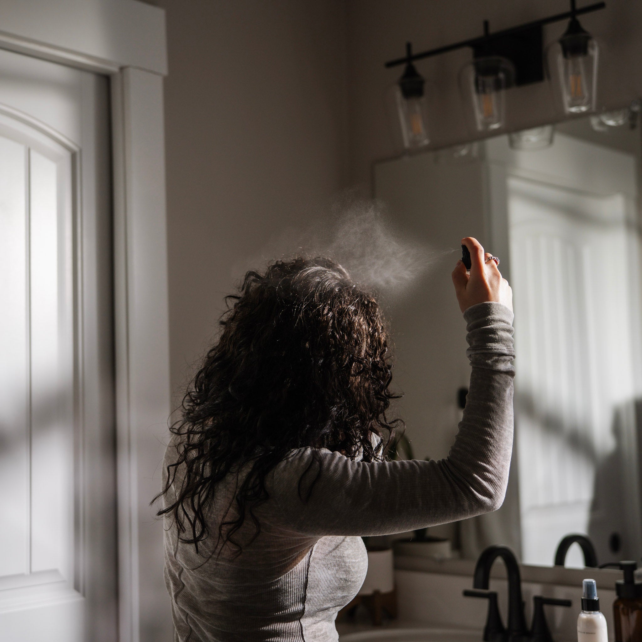 Woman using sea salt spray by the Olive Branch for hair care