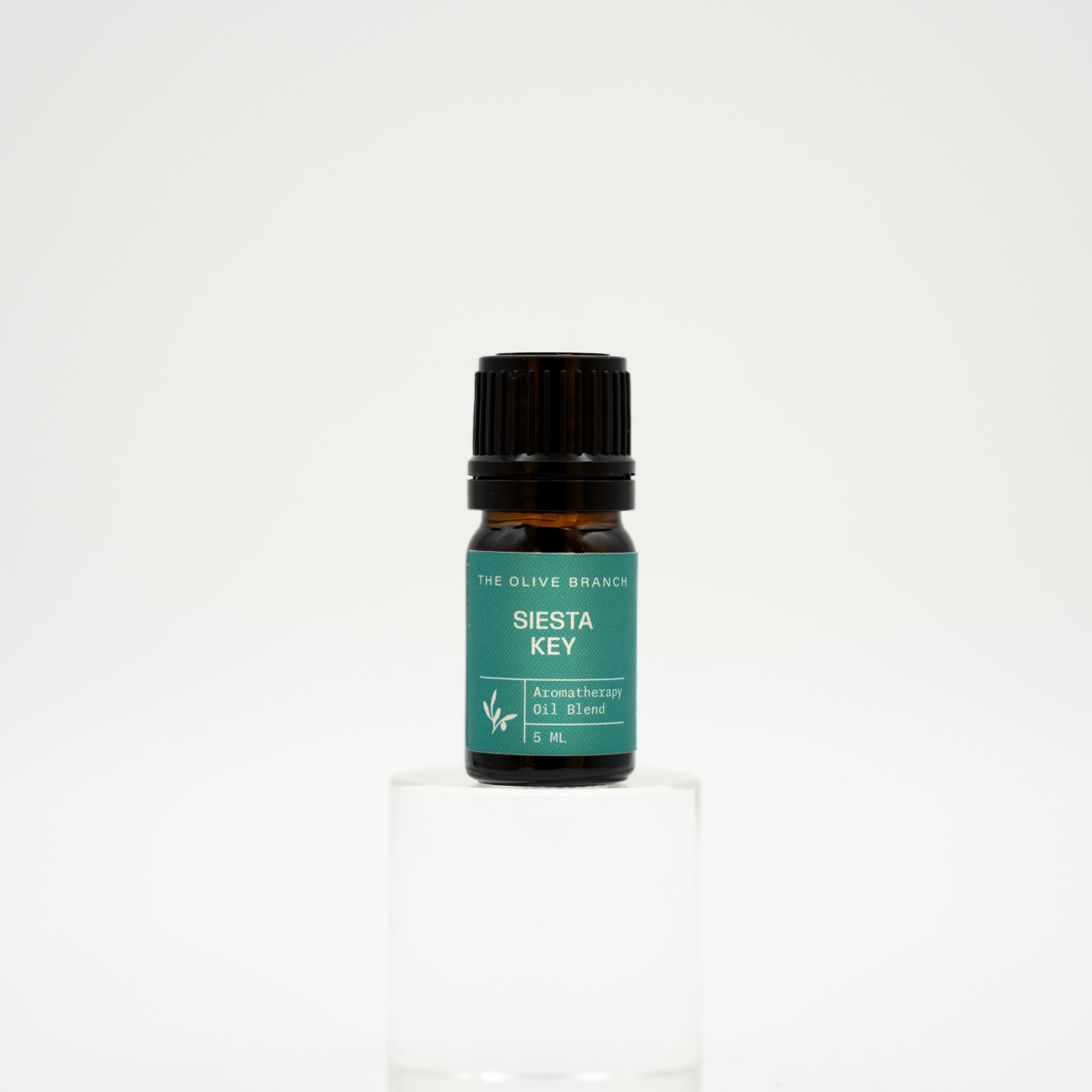 Small bottle of essential oil with a green label on a white background