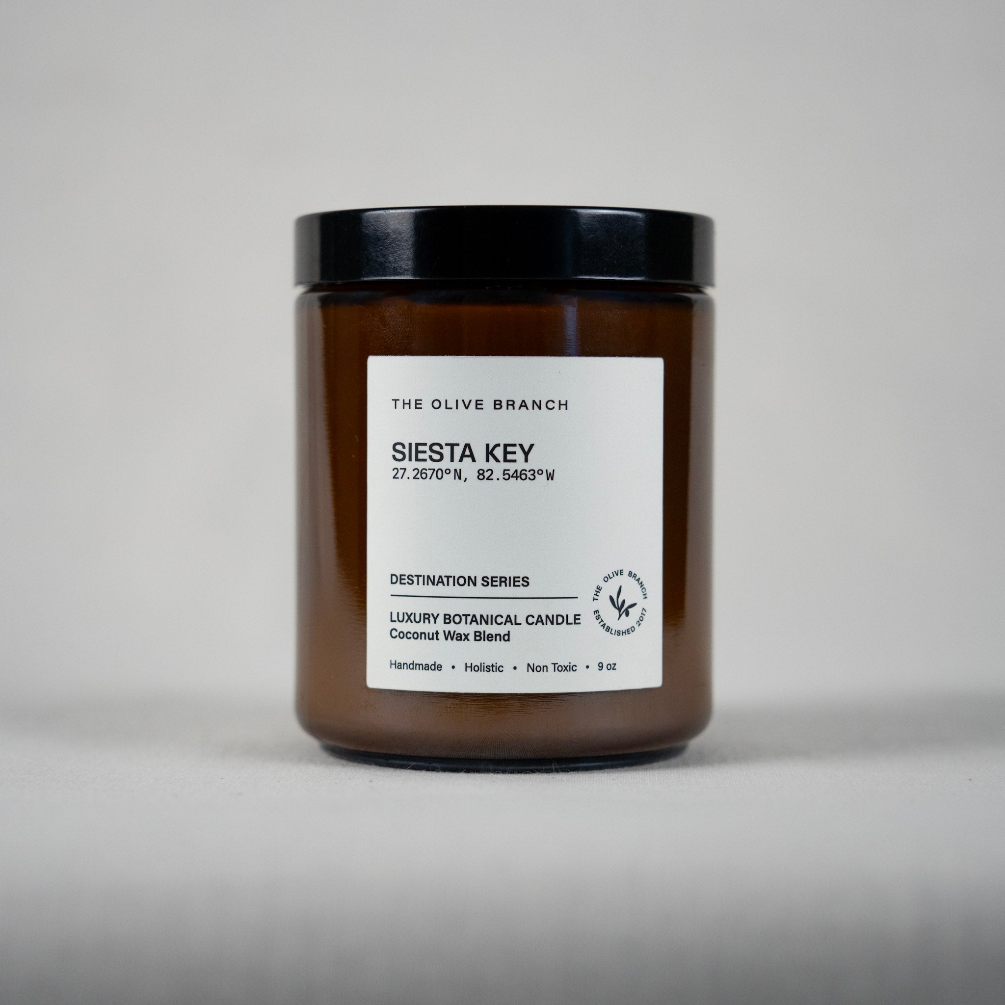 Brown candle jar 'siesta key' with black lid and white label on a gray background