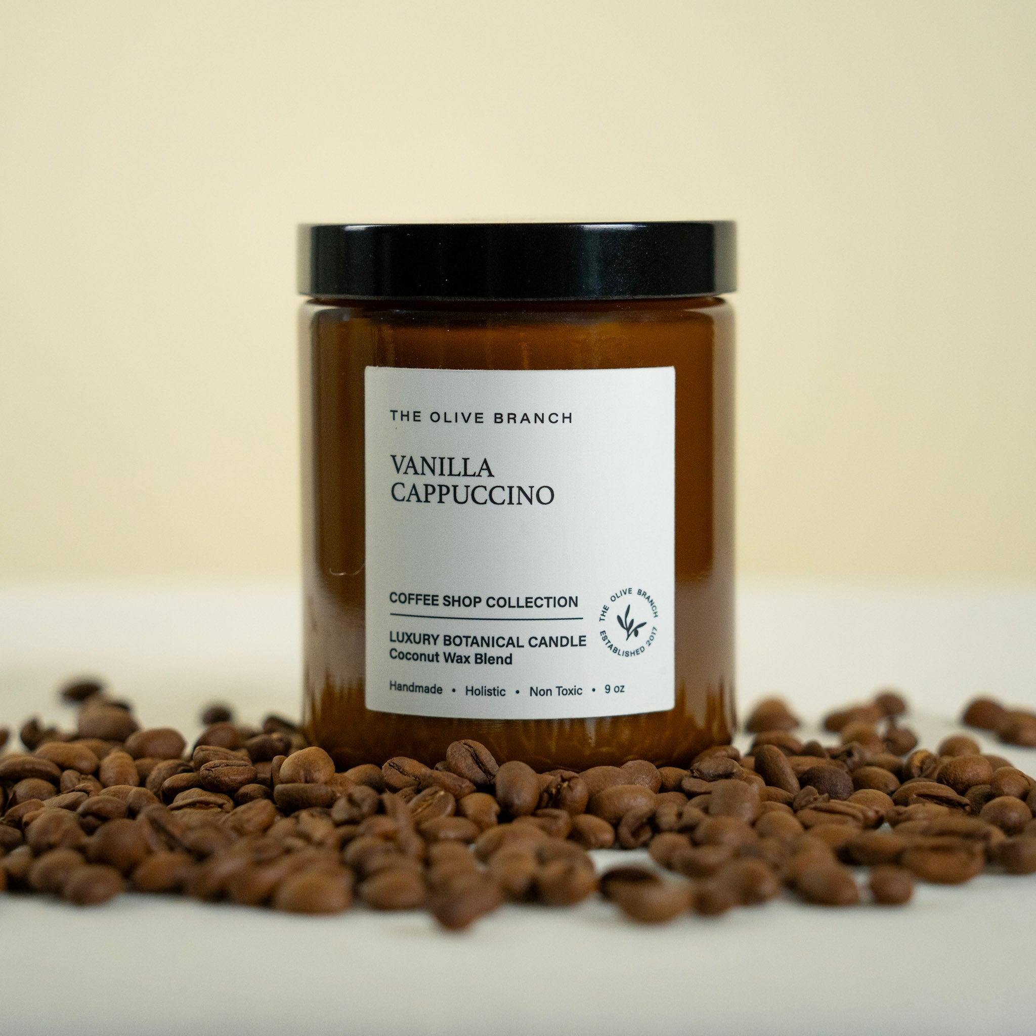 Vanilla cappuccino candle with coffee beans on a beige background